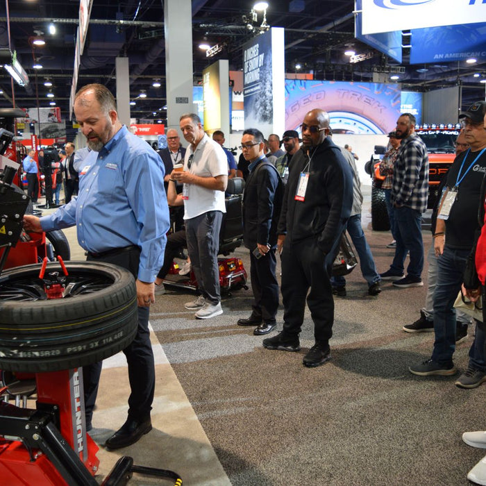 Attendees watch a wheel and tire service equipment demonstration at the SEMA Show